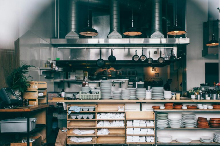 Interior of kitchen in modern restaurant with piles of plates and other different assorted utensils